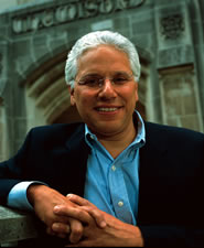 Picture of a man with white hair wearing a light blue shirt with a black suit jacket over on top of it.